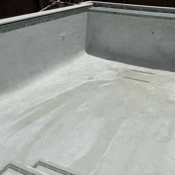 Close up of a pool that was resurfaced with grey concrete.